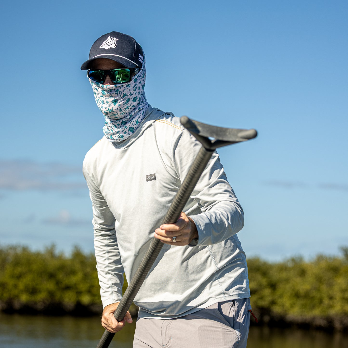 Fishing guide poling a skiff wearing a Drink Conch face mask