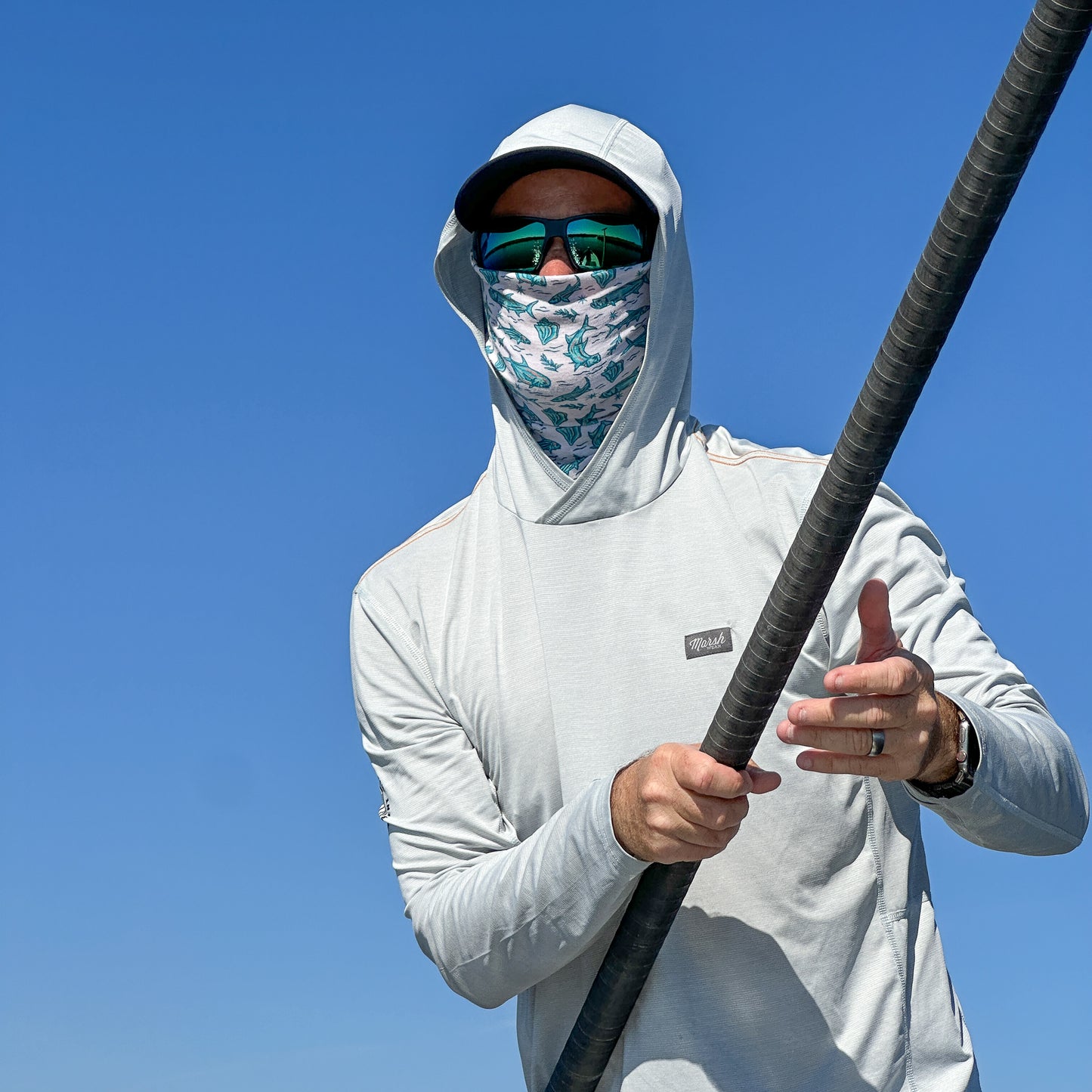 Fishing guide poling a skiff wearing a Drink Conch face mask