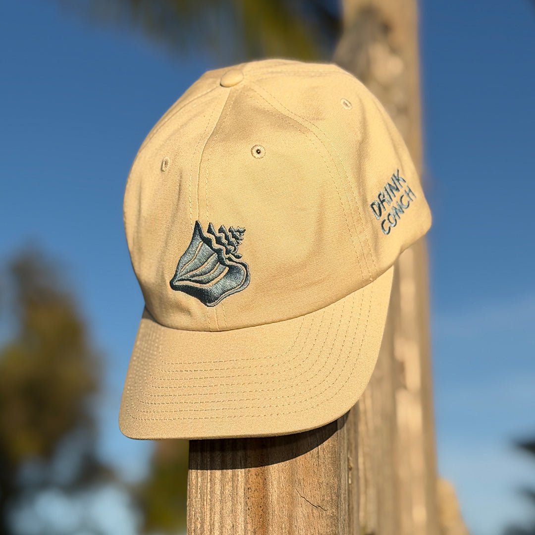 Drink Conch dad hat sitting on wooden post